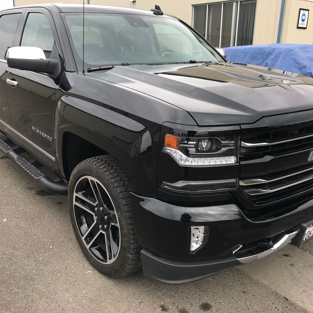 A black truck is parked in front of a building.