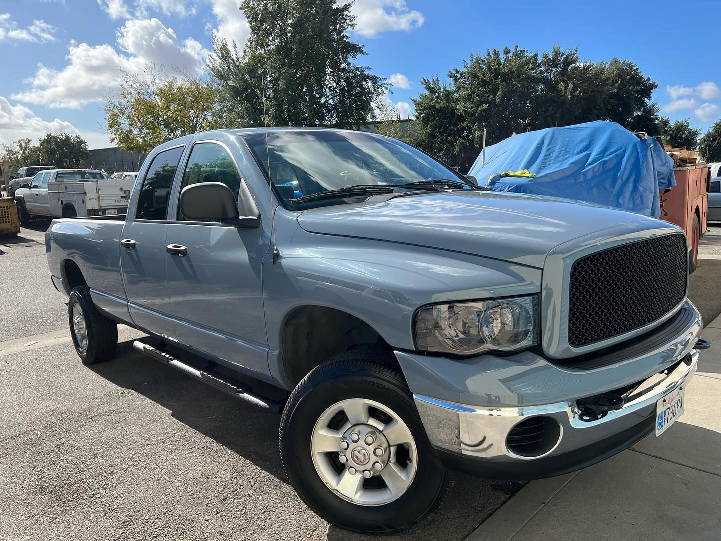 A blue dodge ram truck is parked on the side of the road.