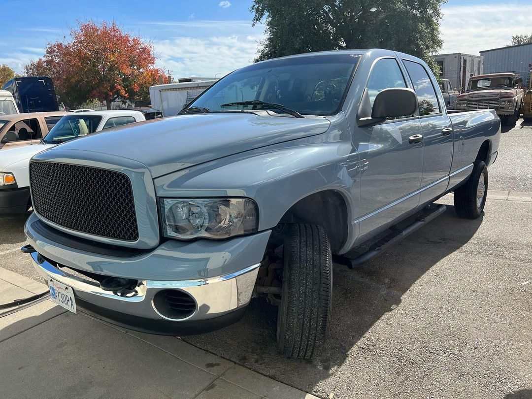 A silver dodge ram truck is parked on the side of the road.