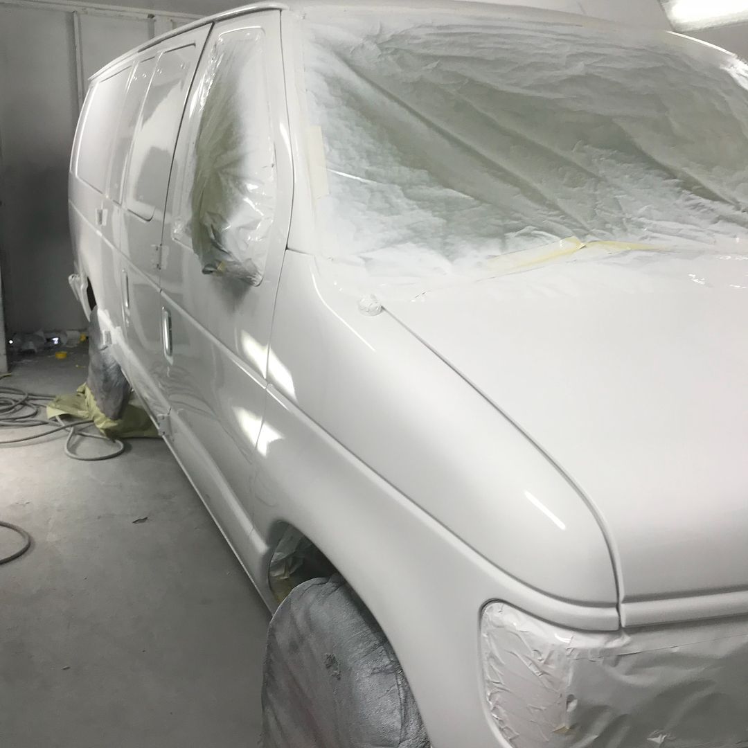 A white van is covered in plastic in a garage.