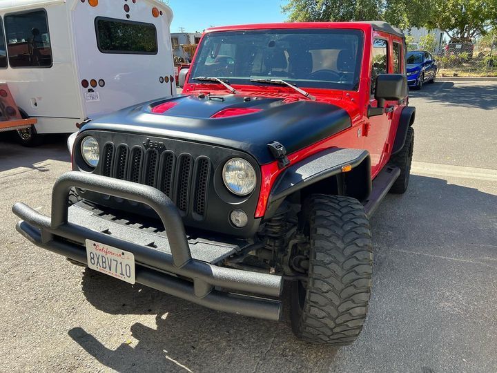 A red and black jeep is parked in a parking lot.