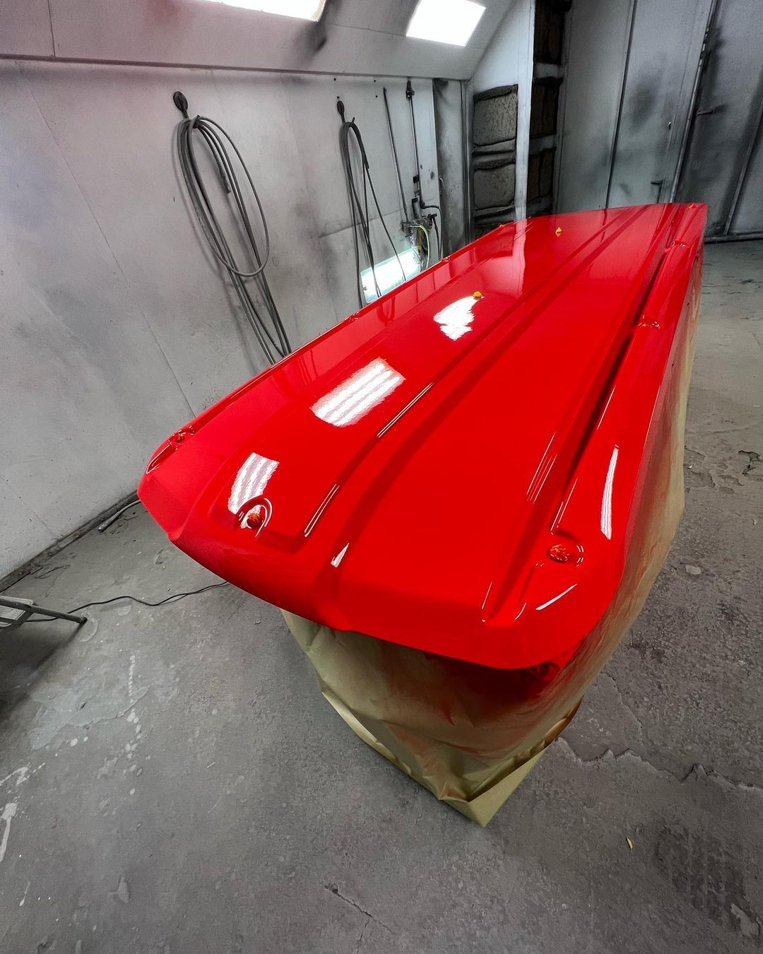 A red boat is painted in a paint booth