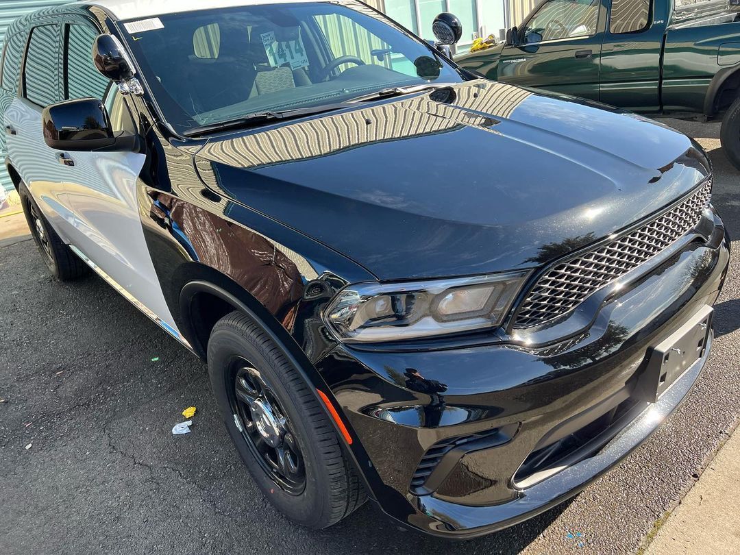 A black and white dodge durango is parked on the side of the road.