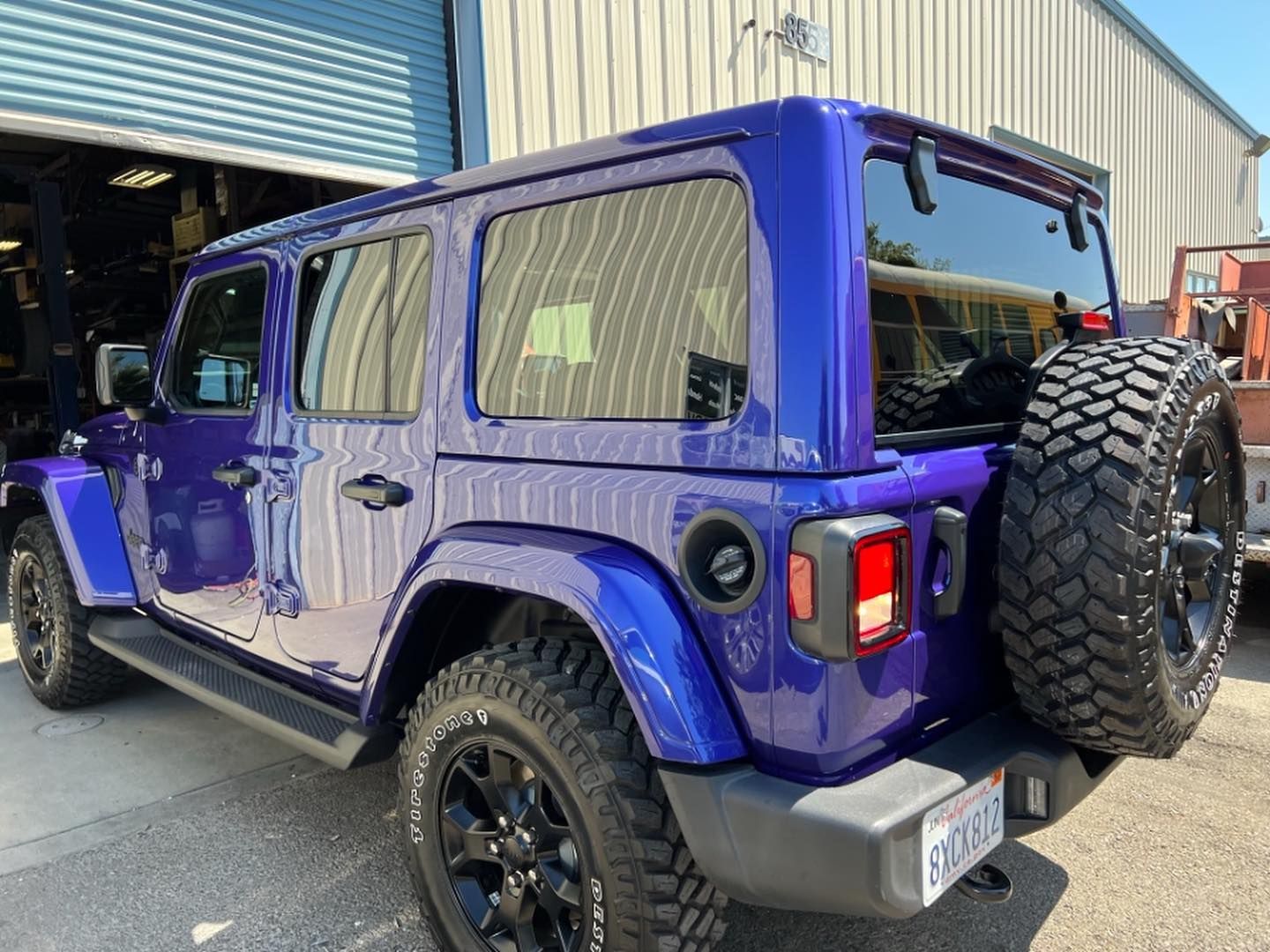 A purple jeep wrangler is parked in front of a building.