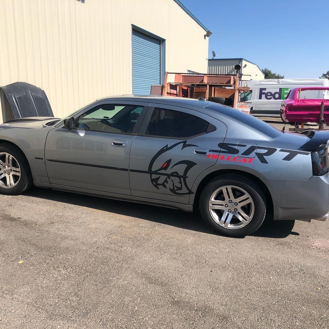 A silver srt car is parked in front of a fedex truck