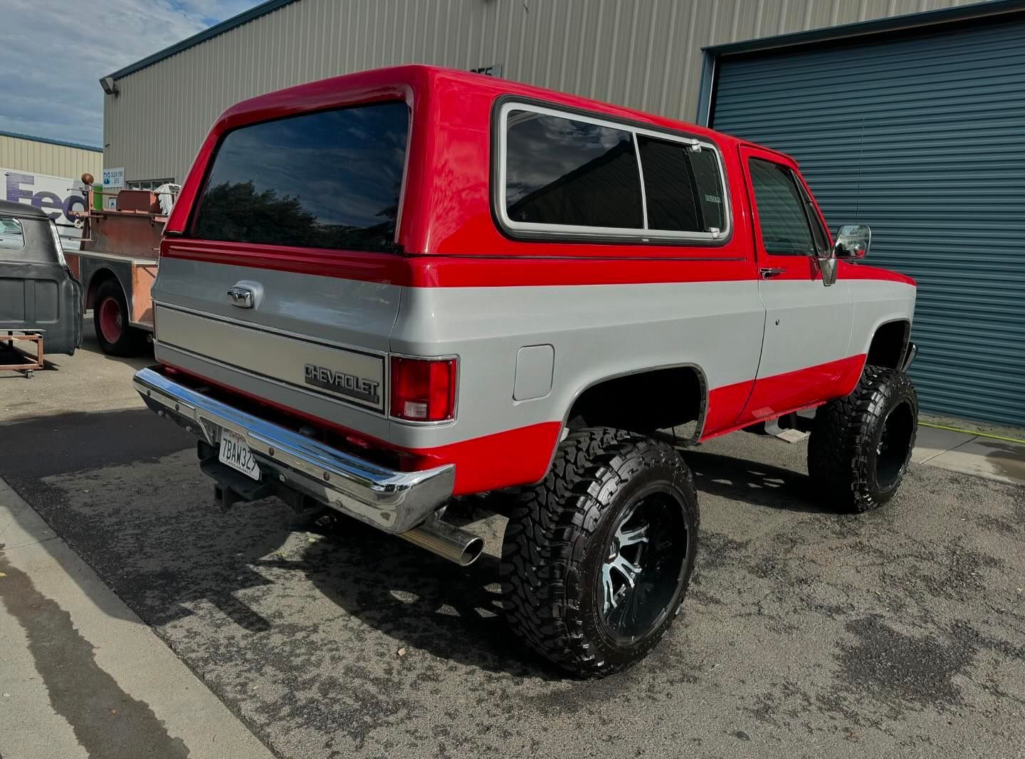 A red and white truck is parked in front of a building.