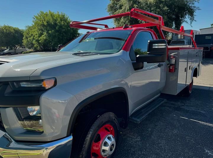 A gray truck with a red bed is parked in a parking lot.