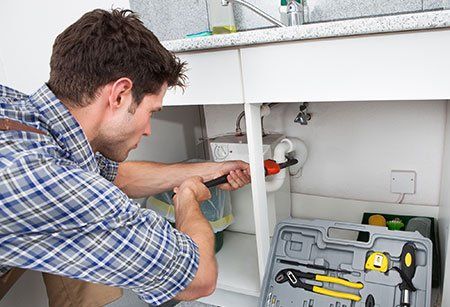 Plumber fixing sink — Plumbing Contractors in Marina, CA Plumber fixing sink — Plumbing Contractors in Marina, CA