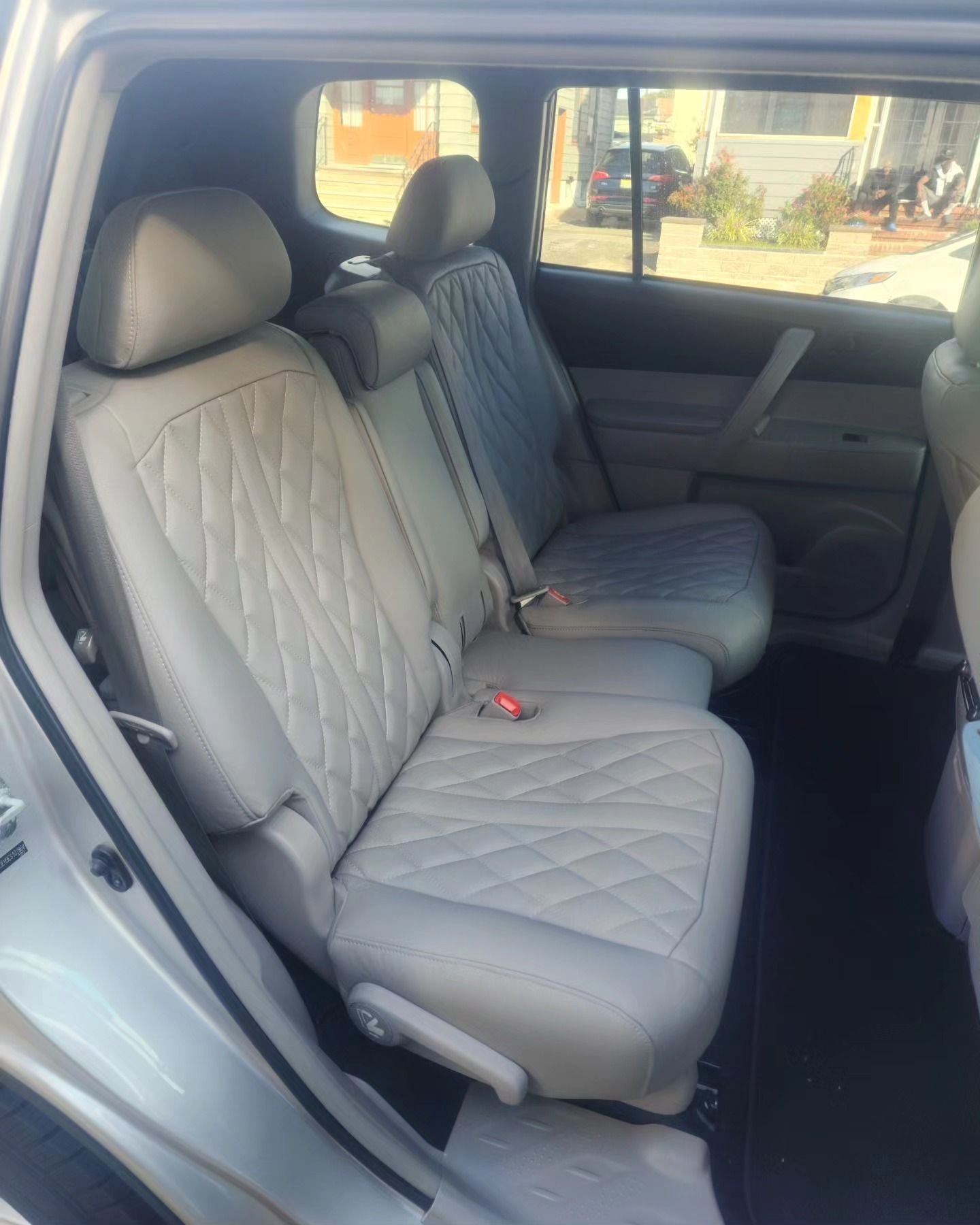 The back seat of a silver car with white seat covers