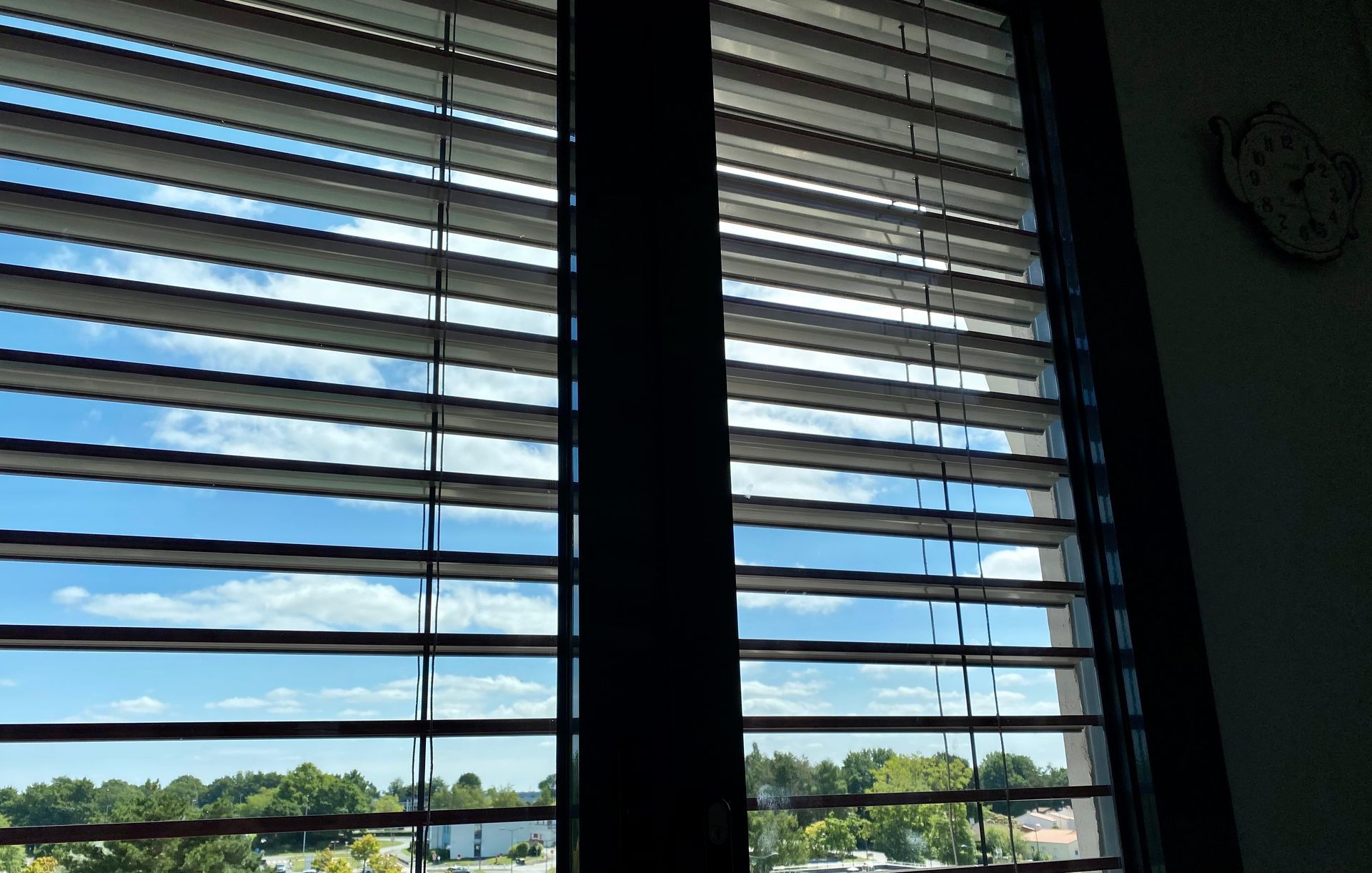 Une fenêtre avec des stores et une horloge sur le mur.