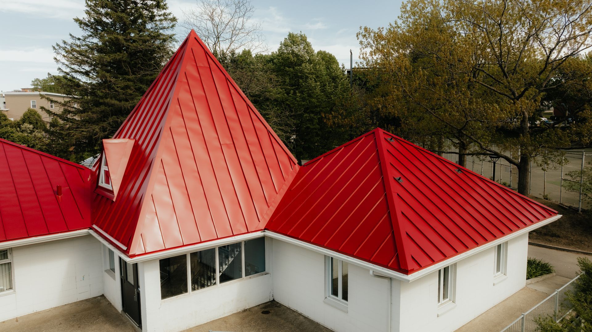 Une maison blanche au toit rouge est entourée d'arbres.