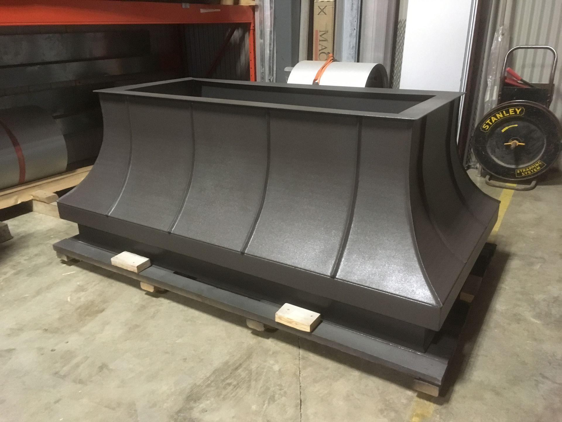 Un gros objet métallique est posé sur une palette dans un entrepôt.