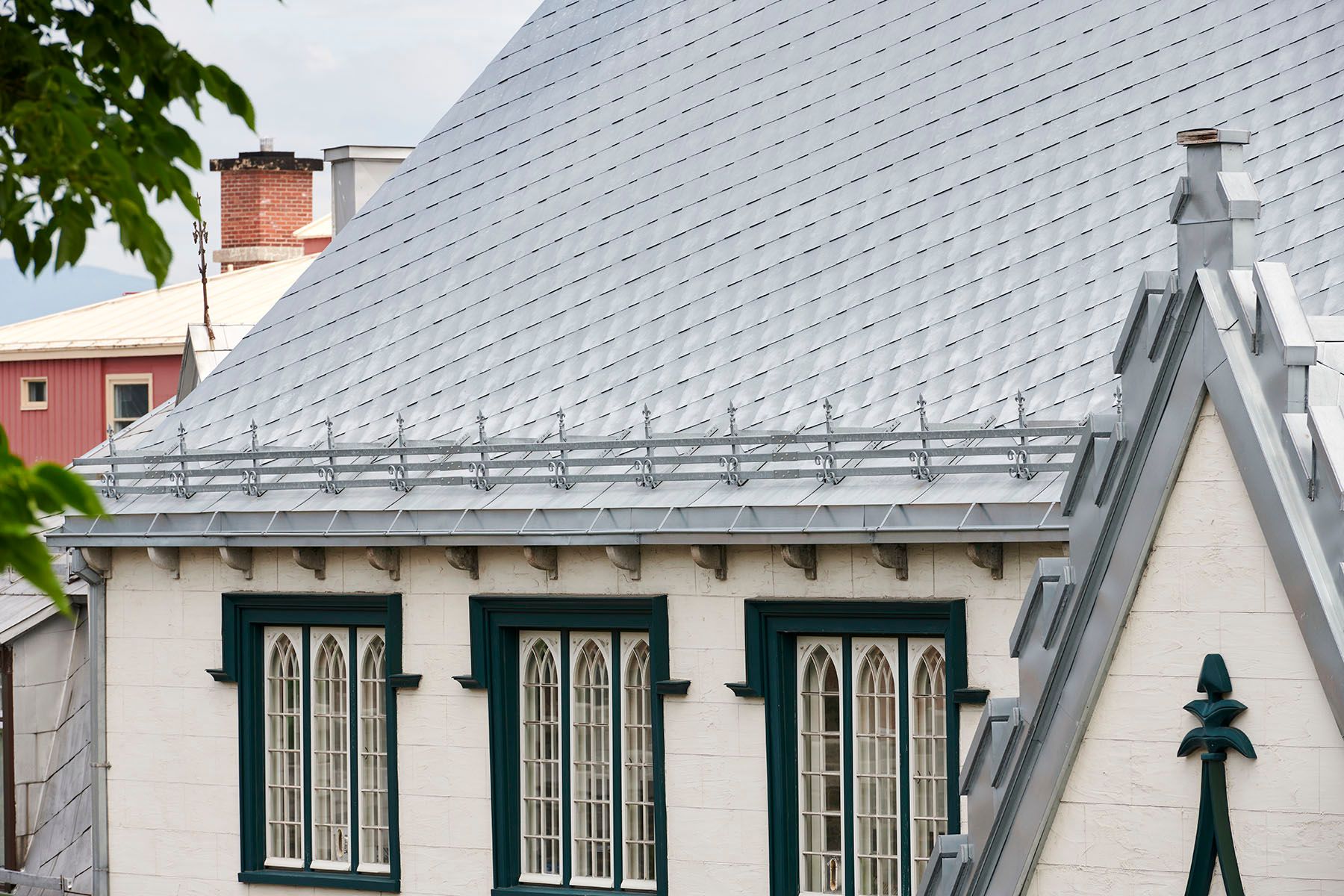 Bâtiment blanc avec toit orné et cadres de fenêtres vert foncé.
