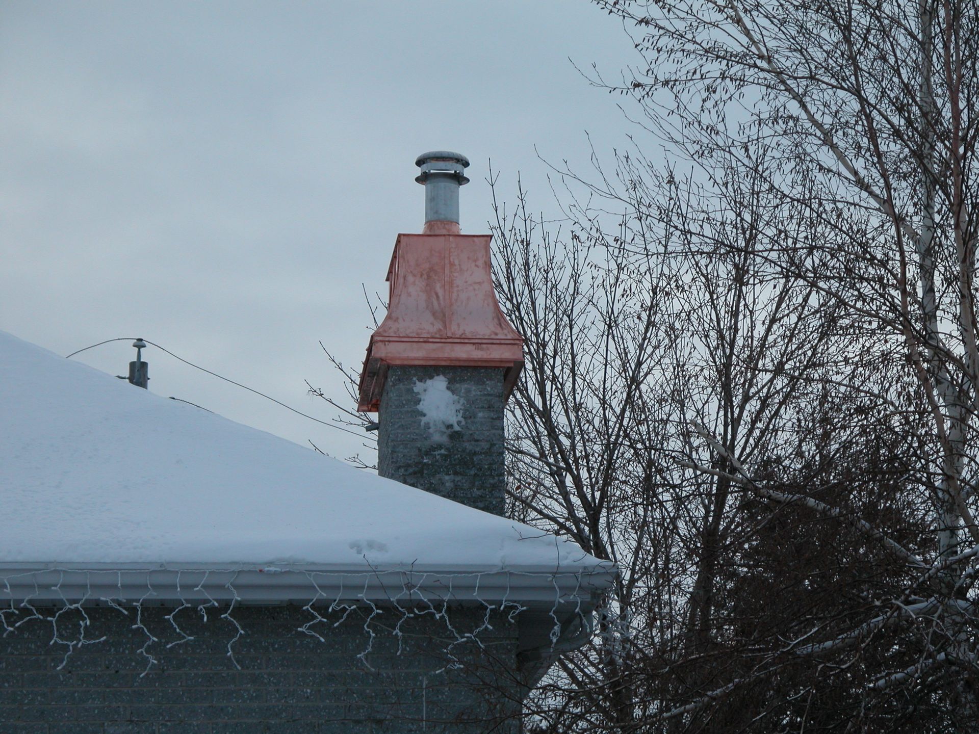 Un toit enneigé avec une cheminée au dessus