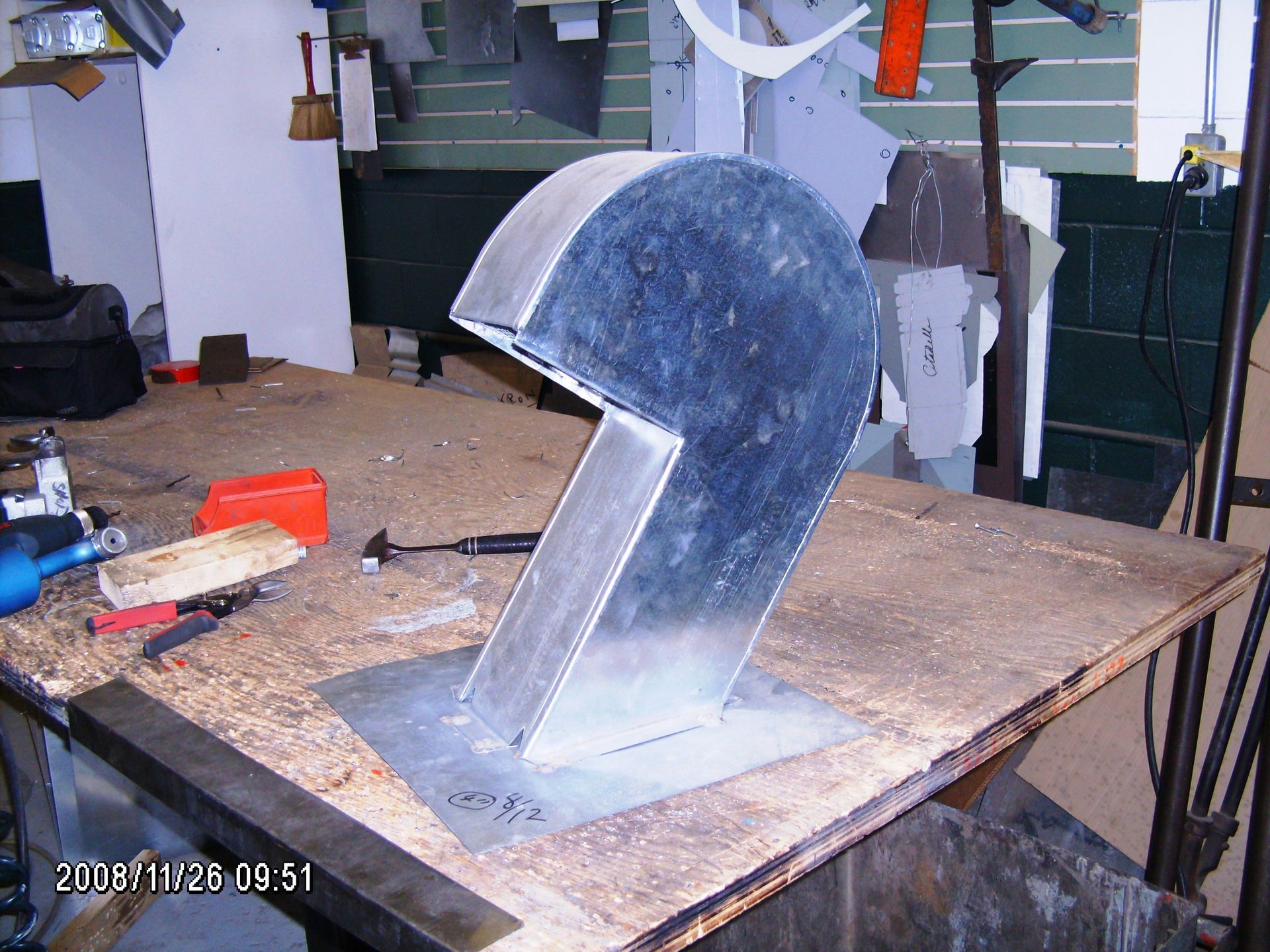 Salle de bains élégante avec miroir arqué, carrelage en mosaïque, toilettes suspendues et meuble-lavabo intégré avec rangements.