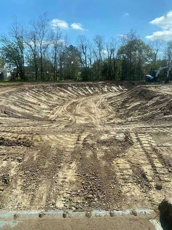 A construction site with a lot of dirt and trees in the background.