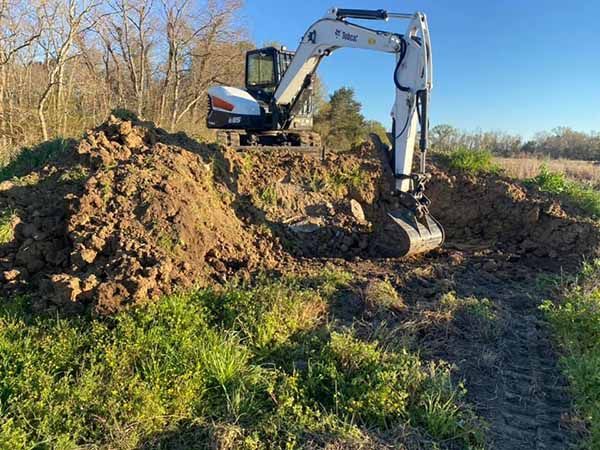 A bulldozer is digging a hole in the dirt in a field.