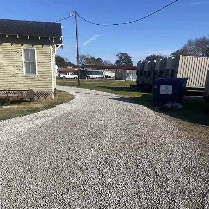 A gravel driveway leading to a house and a truck