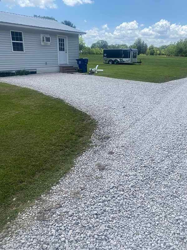 A white house with a gravel driveway leading to it.
