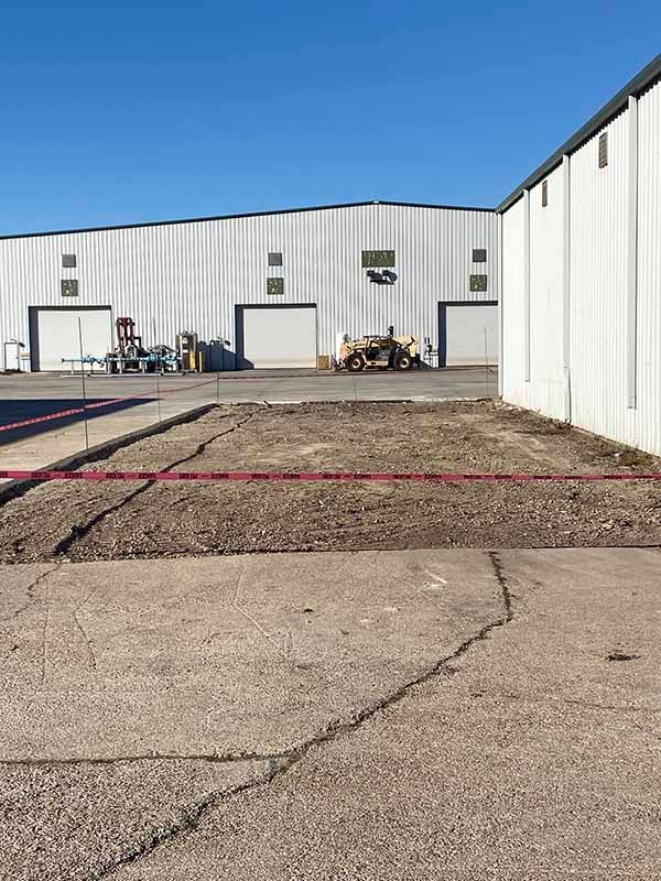 A large warehouse with a lot of machinery parked in front of it.