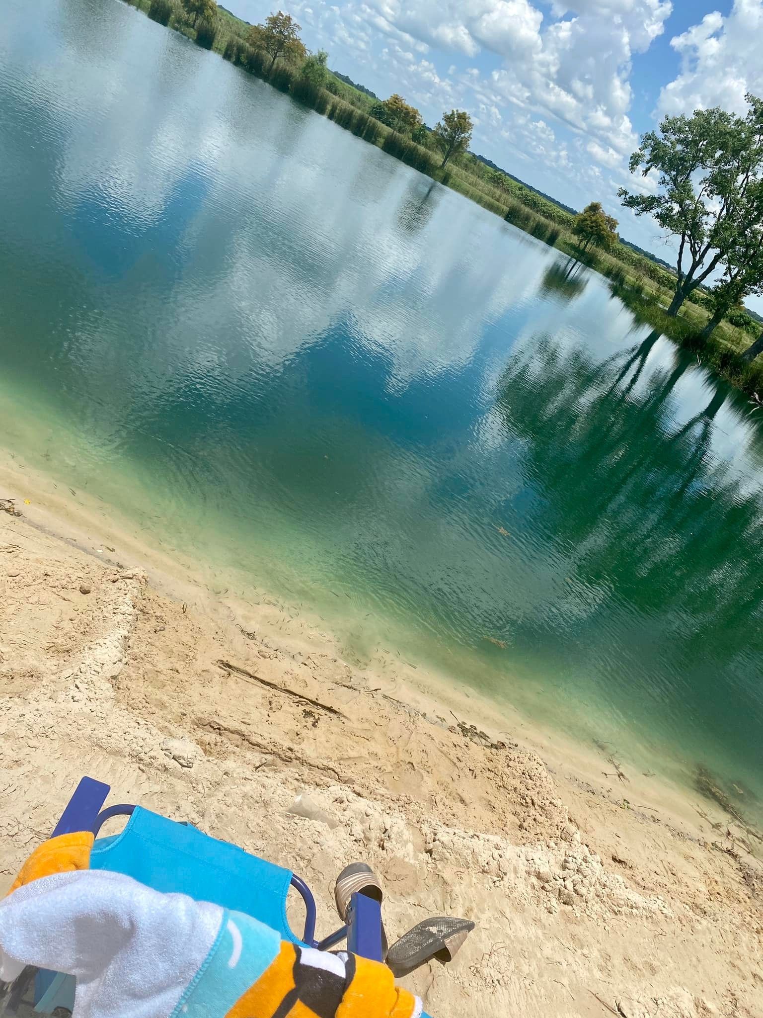 A beach chair is sitting on the sand next to a body of water.