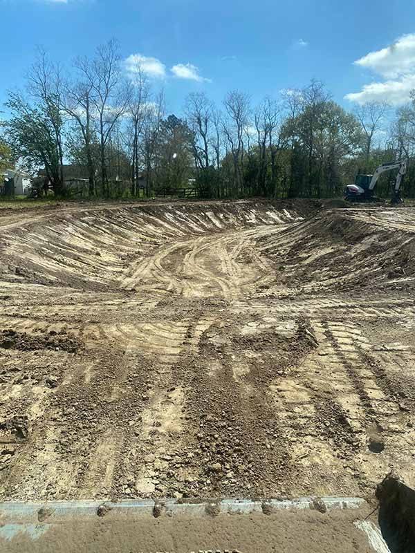 A construction site with a lot of dirt and trees in the background.