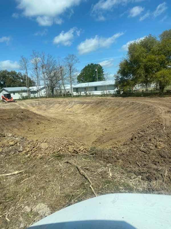 A large dirt field with a house in the background.