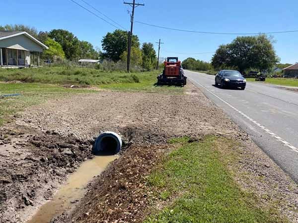 A car is driving down a road next to a tractor.