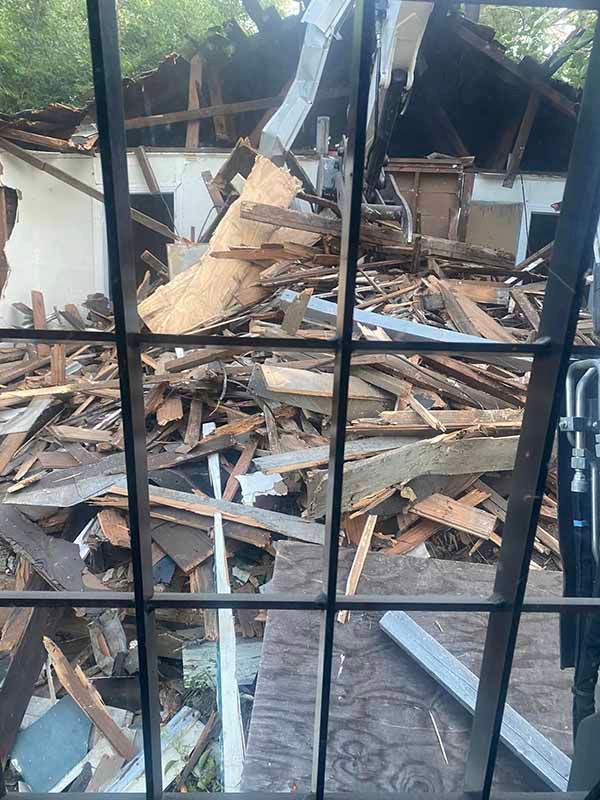 A pile of wood is sitting in front of a building that has been demolished.