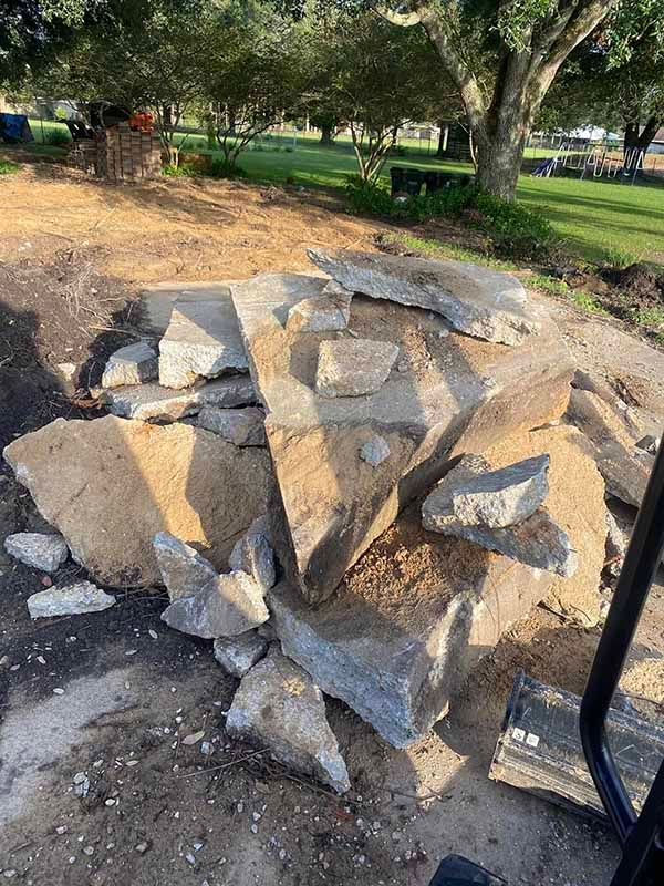 A pile of rocks is sitting on the ground in a park.