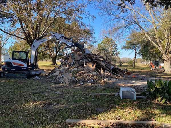A bulldozer is moving a pile of wood in a field.
