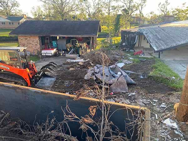 A tractor is moving dirt in front of a house.