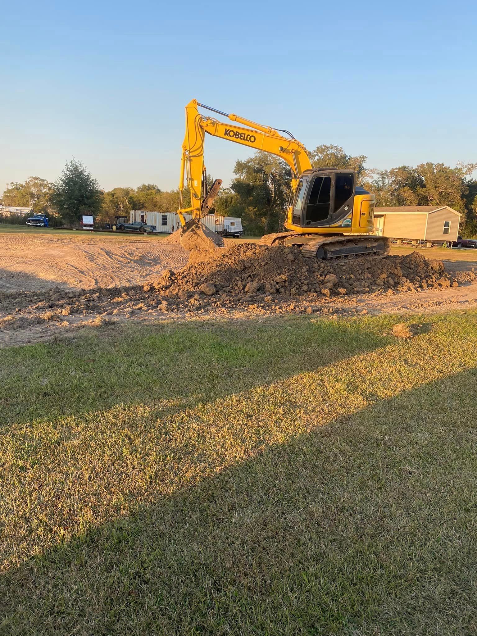 A yellow excavator is digging a hole in a field.