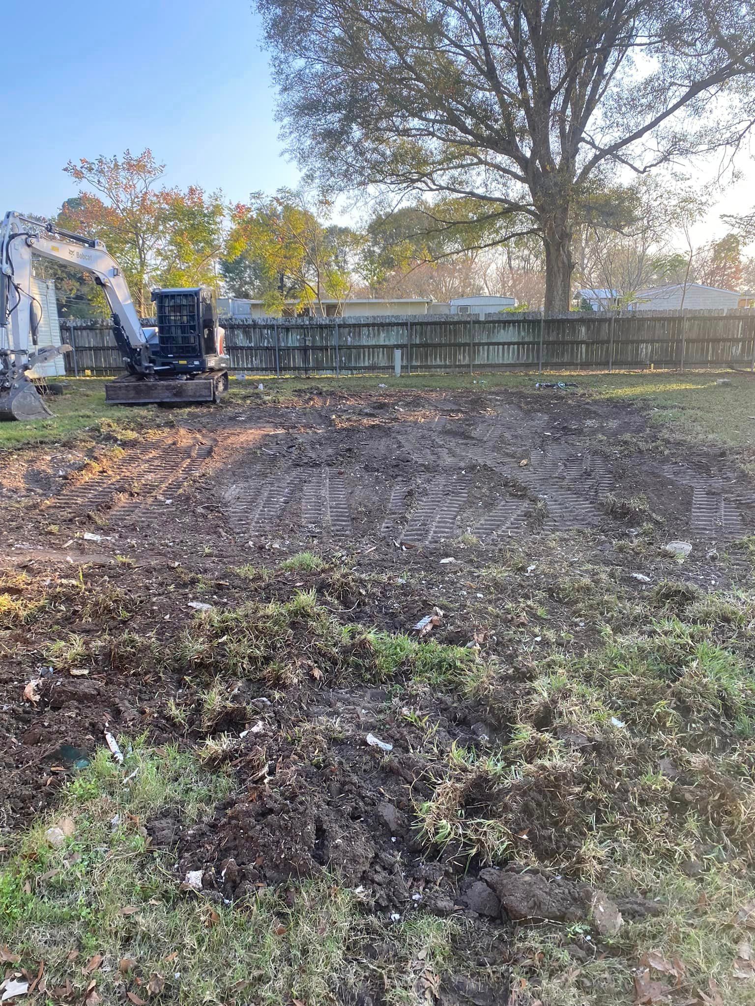 An excavator is digging a hole in the dirt in a yard.