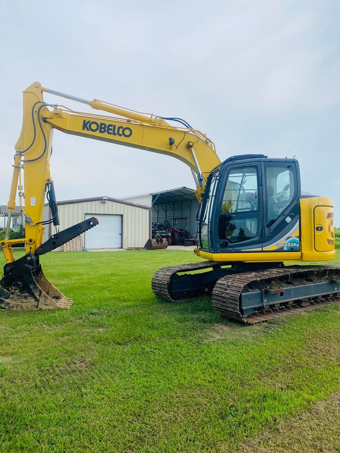 A yellow excavator is parked in a grassy field.