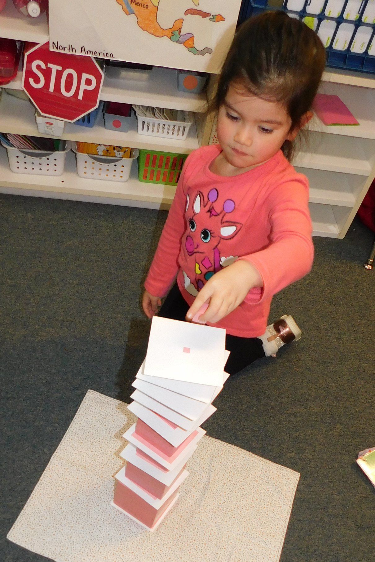 Young girl stacking cards, concentrating, in a classroom setting