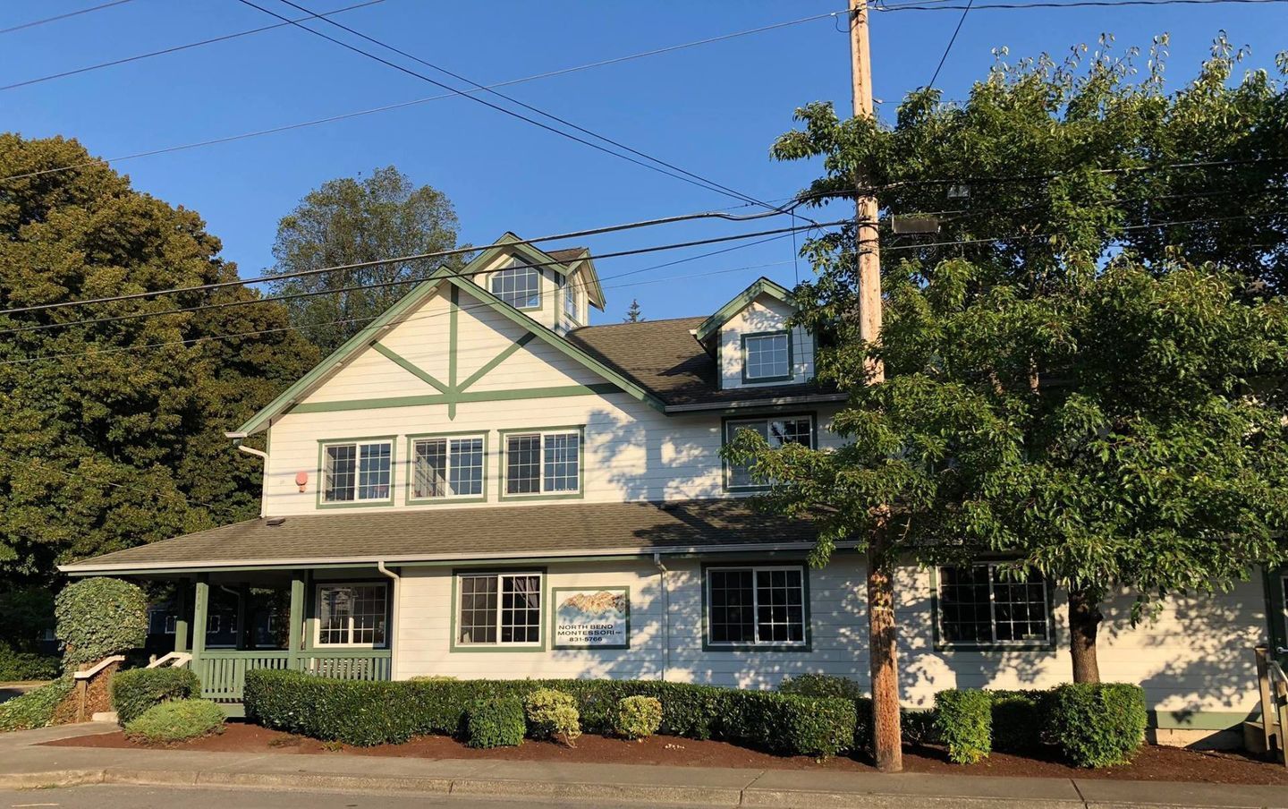 White two-story building with green trim, windows, and porch