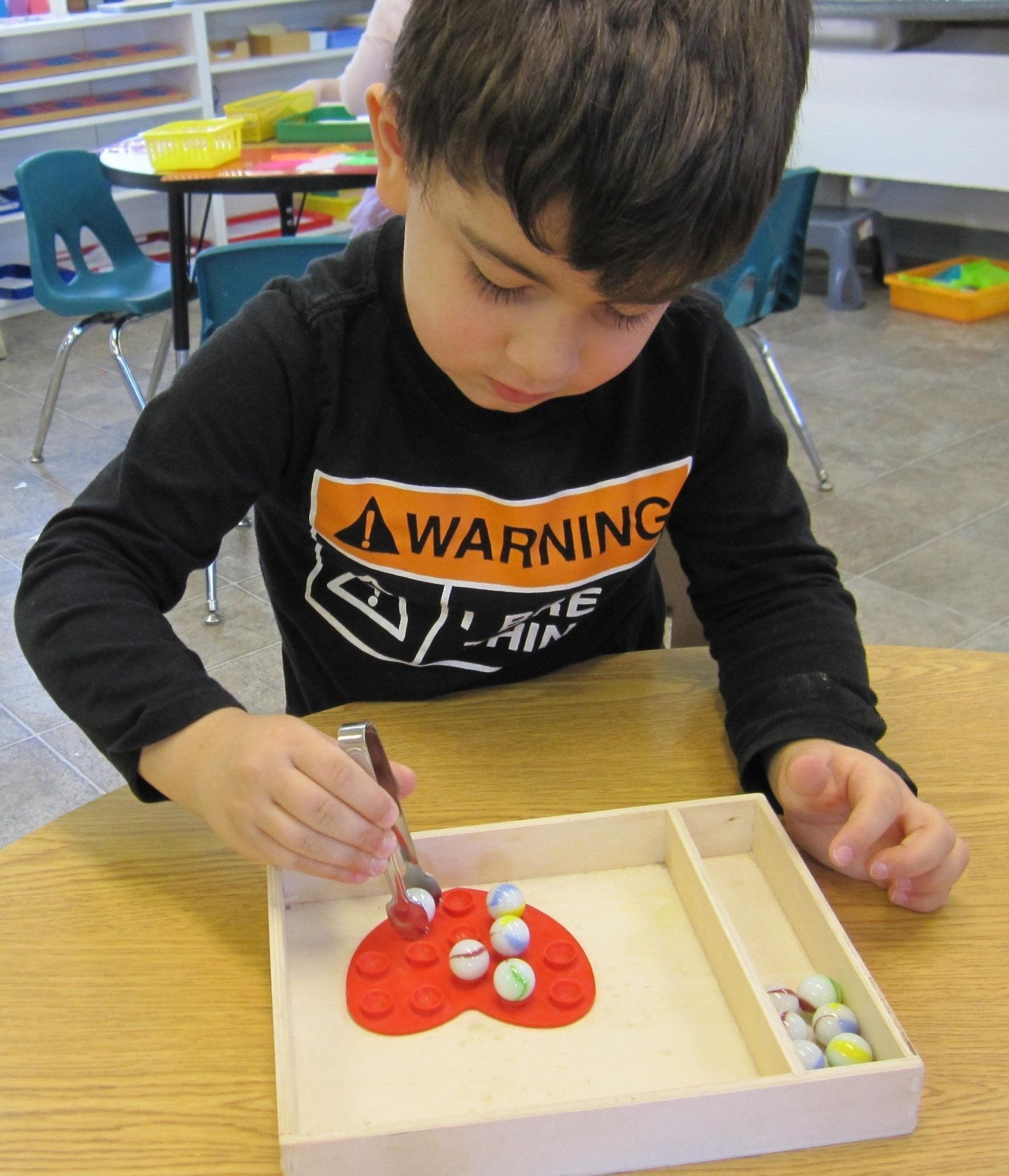 A young boy uses tweezers