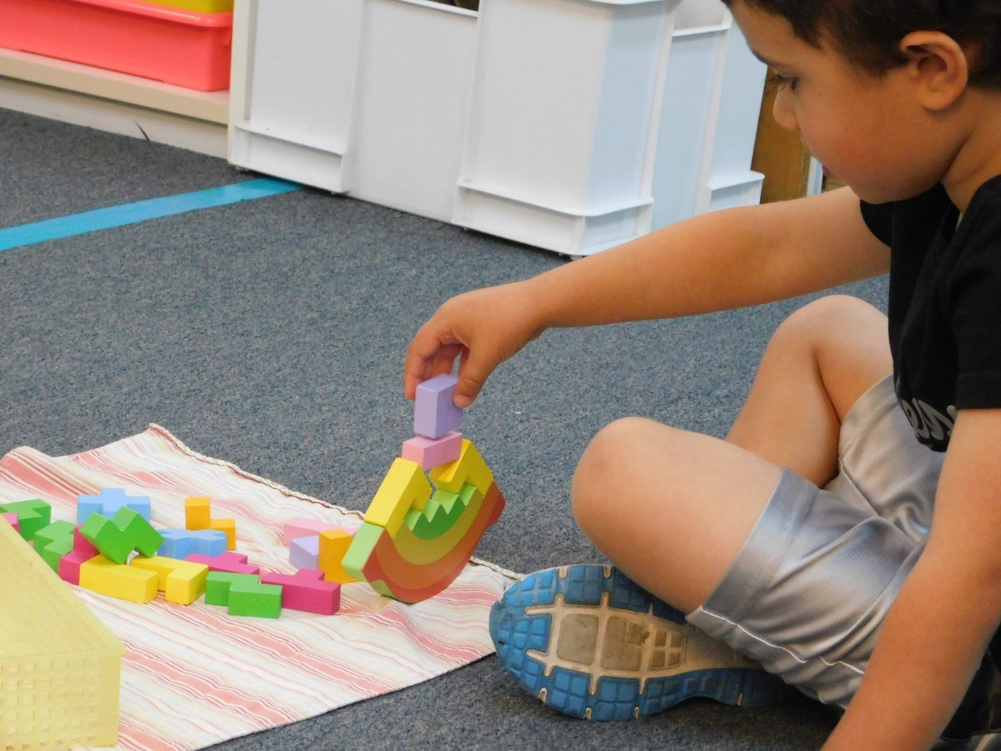 Young boy building with colorful blocks on a rug