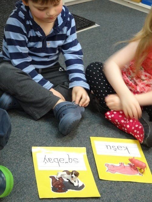 Two children seated on floor with flashcards