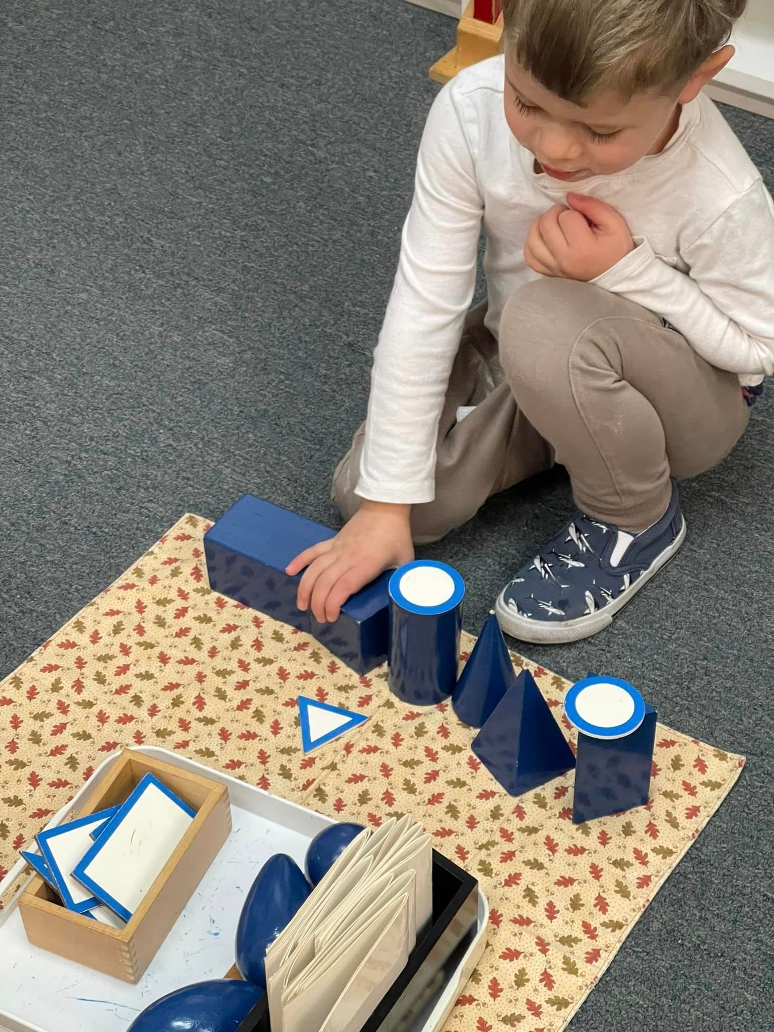 Young child playing with blue geometric shapes on a patterned mat