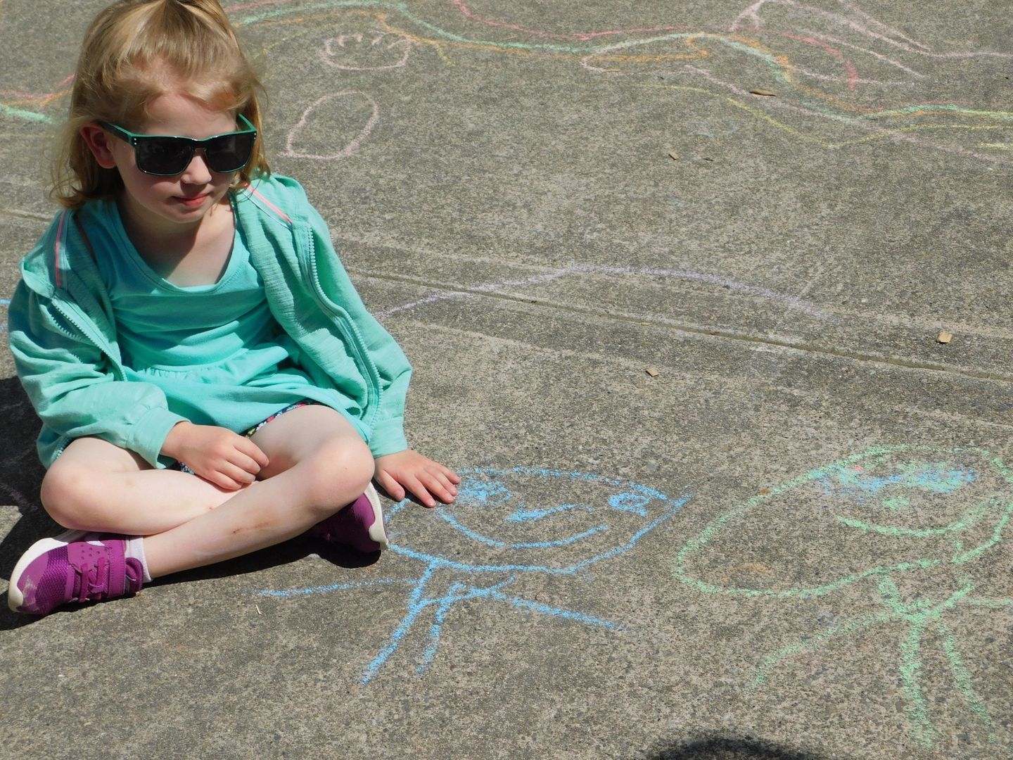 Girl in sunglasses sits on pavement