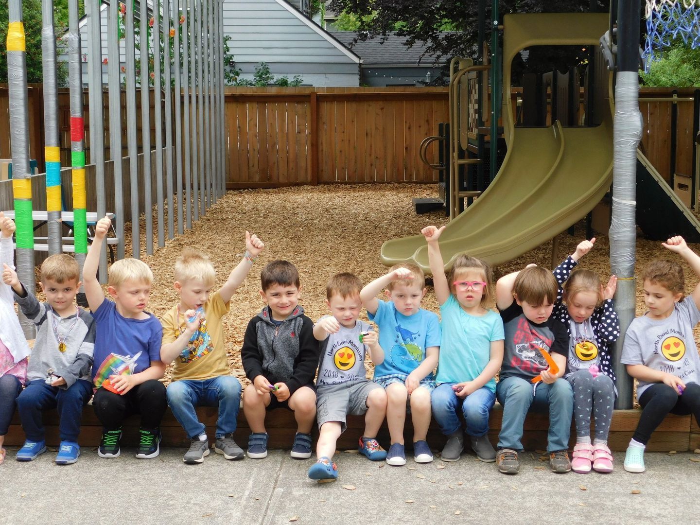 Group of children seated outdoors, raising fists in the air