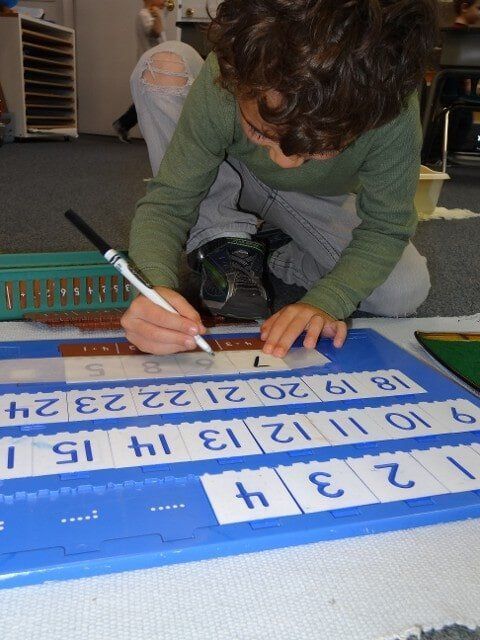 Boy writing on number cards in a classroom