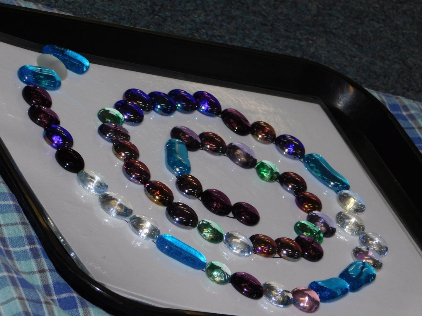 Colorful glass beads arranged in a spiral on a white tray