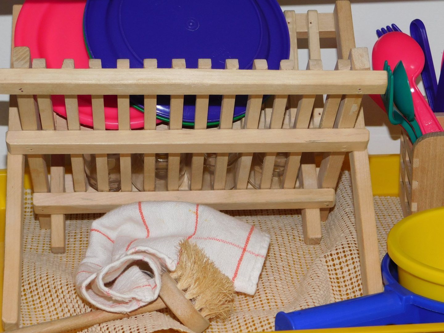 Wooden dish rack with pink and blue plates, and dish towel