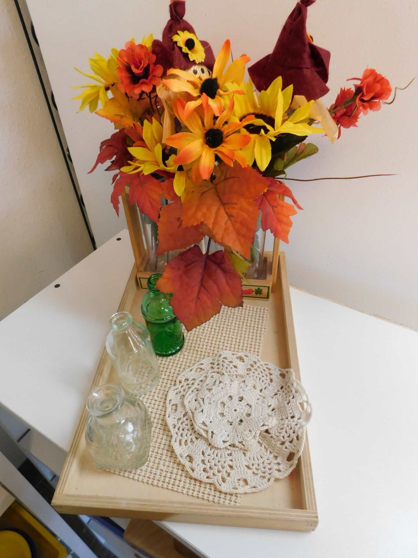 Autumn floral arrangement with tray, two vases, and doilies on a white table