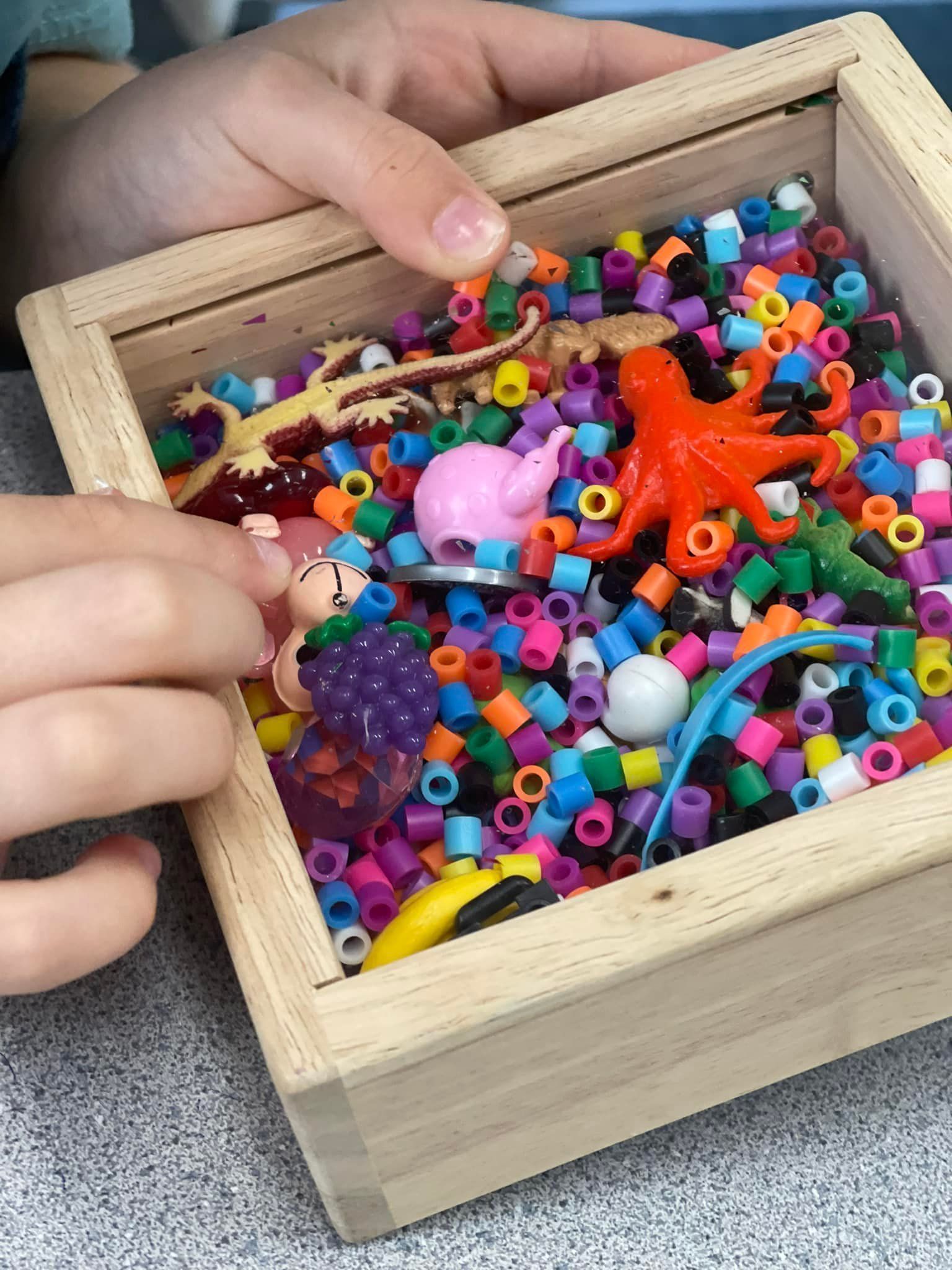 Child's hands playing in a wooden box