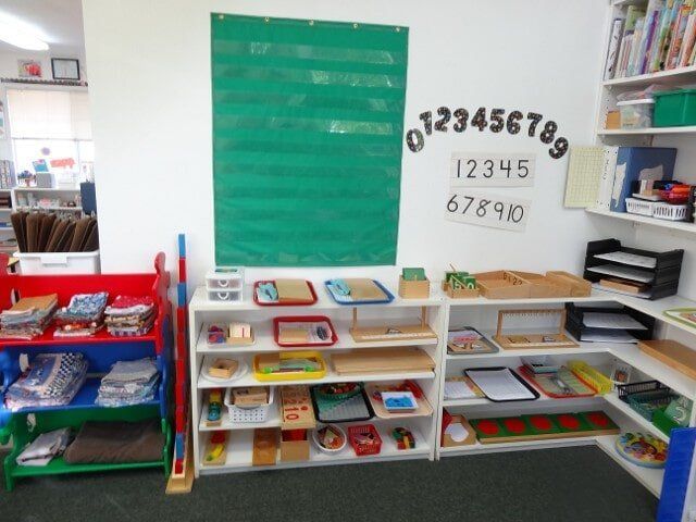Montessori classroom with shelves of learning materials, numbers display, and chart