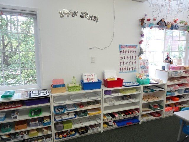 A Montessori classroom with shelves of educational materials, near windows with a view of trees